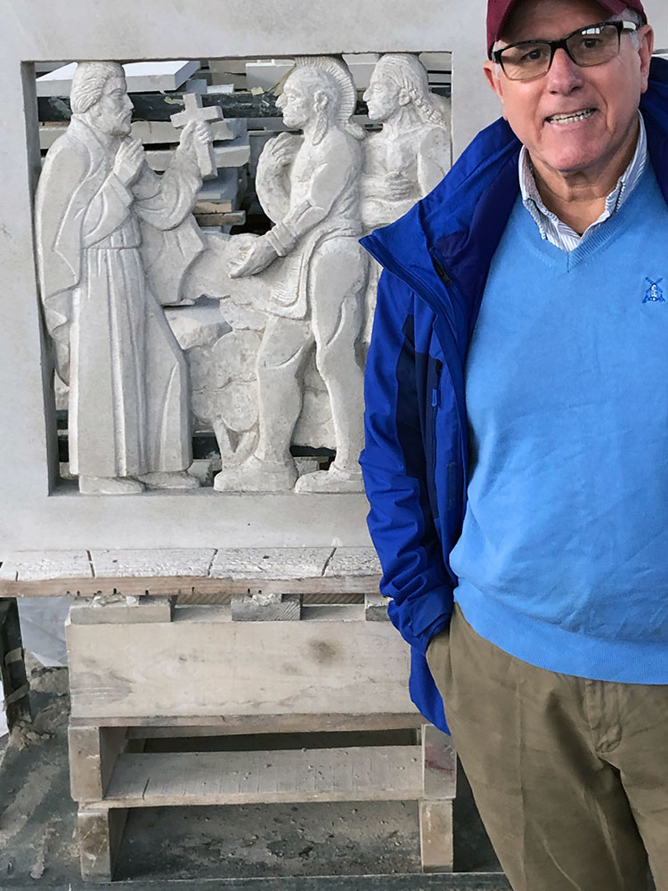 Ralph Petrillo standing next to a carving of Ignatius Loyola 